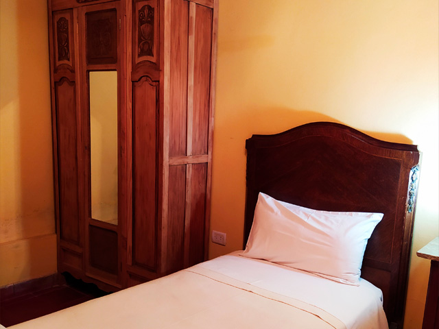 cama individual con sommier de madera y placar lateral de madera con un espejo